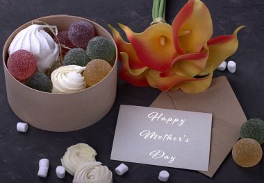 Kırmızı Sarı callas marshmallow marmelat ahşap yuvarlak kutu ve mutlu anneler günü gri beton zemin üzerine yazı ile zarf ile buket.