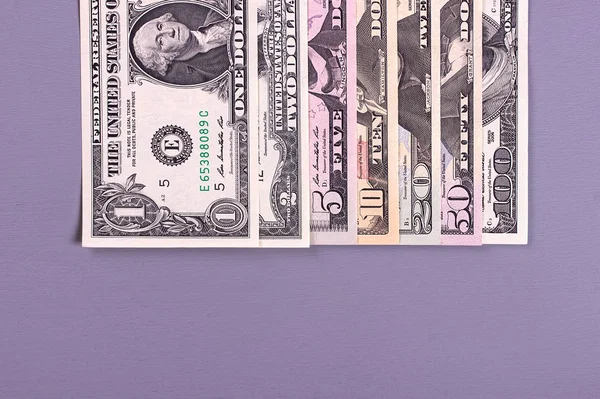 Pilha de notas de dólar de diferentes denominações em fundo cinza . — Fotografia de Stock