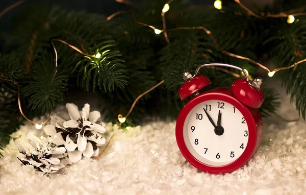 Χριστουγεννιάτικο φόντο με κόκκινο ρολόι συναγερμών νιφάδες χιονιού κώνοι και κώνοι. — Φωτογραφία Αρχείου