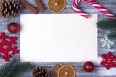 Noel dekorasyon tebrik kartı kırmızı kar taneleri turuncu şeker kamışı gri ahşap arka plan.