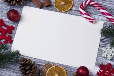 Noel dekorasyon tebrik kartı kırmızı kar taneleri turuncu şeker kamışı gri ahşap arka plan.