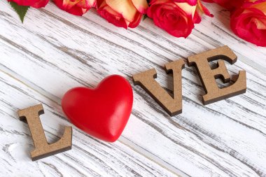 Ahşap harf kelime aşk ve pembe Gül çiçek Beyaz ahşap arka plan üzerinde.