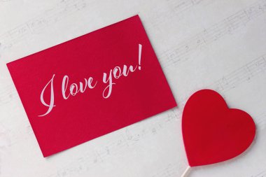 Sevgililer günü tebrik kartı kırmızı kalp beyaz kağıt arka plan ve yazı ile.