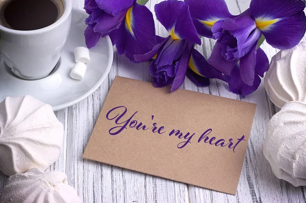 Tarjeta de felicitación del día de San Valentín iris flor púrpura café taza malvavisco y letras . —  Fotos de Stock