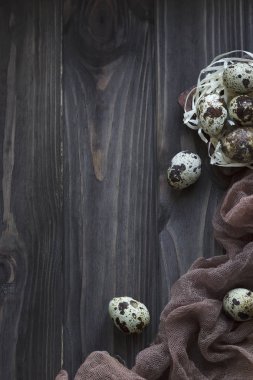Paskalya dekorasyon tüyler Bıldırcın yumurta, kahverengi gri kumaş ahşap arka plan.