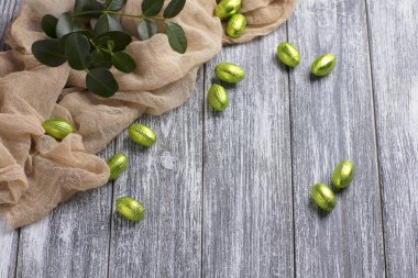 Çikolata Paskalya yumurtaları folyo ile gri ahşap zemin üzerine bej kumaş.