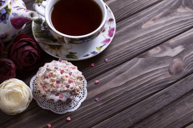 Demlik çay bardağı ve kek üzerine kahverengi ahşap masa.