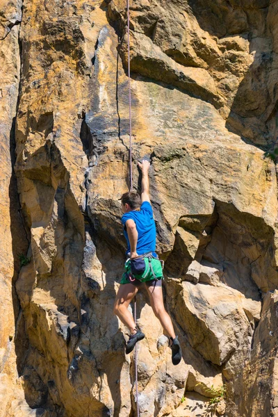 Male rock climber climbing up a cliff — Stock Photo, Image