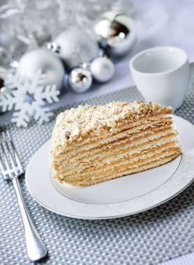 Katman pastasından muhallebi ve bir plaka üzerinde ceviz ile Noel topları arka planda