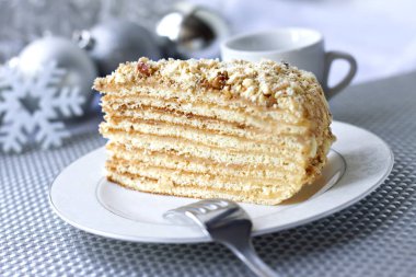 Katman pastasından muhallebi ve bir plaka üzerinde ceviz ile Noel topları arka planda