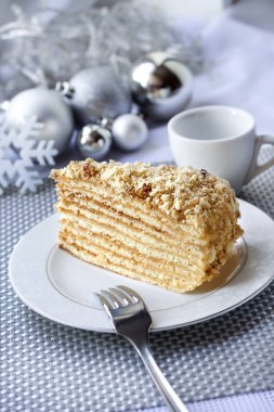 Katman pastasından muhallebi ve bir plaka üzerinde ceviz ile Noel topları arka planda