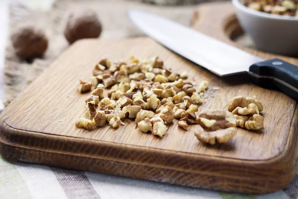 Chopped walnuts on wooden cutting board — Stock Photo, Image
