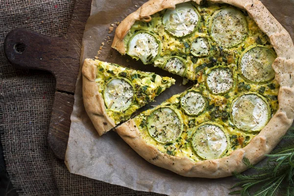 Homemade courgette and goat cheese pie on a dark rustic wooden board background — Stock Photo, Image