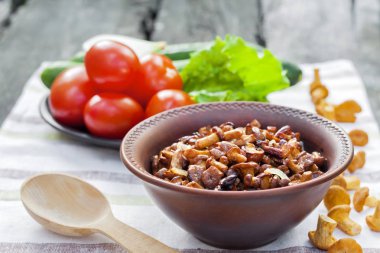 Arka planda salata için taze sebzeler ile rustik kase ve plaka soğan ile Fried chanterelles