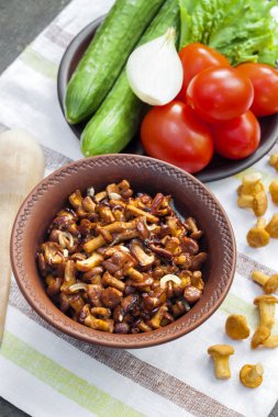 Arka planda salata için taze sebzeler ile rustik kase ve plaka soğan ile Fried chanterelles