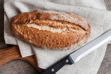 Mutfak masasında kepekli ekmek ahşap tahta somun. Düz döşeme, üst görünüm
