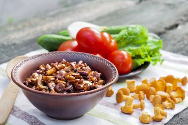 Arka planda salata için taze sebzeler ile rustik kase ve plaka soğan ile Fried chanterelles