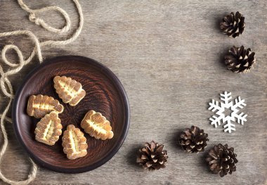 Kırsal kış kompozisyonu tabakta kurabiyeler ve kozalaklarla