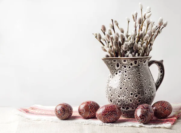 Pâques nature morte avec Pysanka et branches de saule dans une cruche en céramique sur un tissu ukrainien traditionnel. Œufs de Pâques décorés, traditionnels pour la culture de l'Europe de l'Est. Espace de copie — Photo