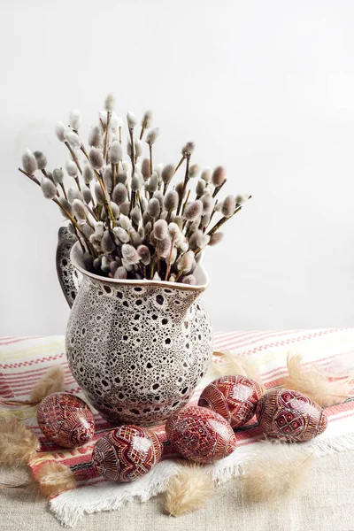 Pâques nature morte avec Pysanka et branches de saule dans une cruche en céramique sur un tissu ukrainien traditionnel. Œufs de Pâques décorés, traditionnels pour la culture de l'Europe de l'Est. Espace de copie — Photo