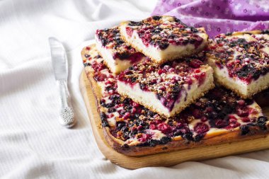 Çilekli lezzetli turta ve ahşap bir tahtanın üzerinde dilimlenmiş süzme peynir.