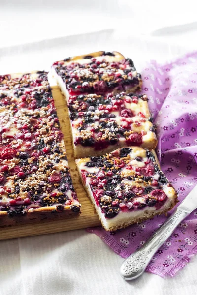 Вкусный пирог с ягодным ассортиментом и творогом нарезанный на квадратные ломтики на деревянной доске — стоковое фото