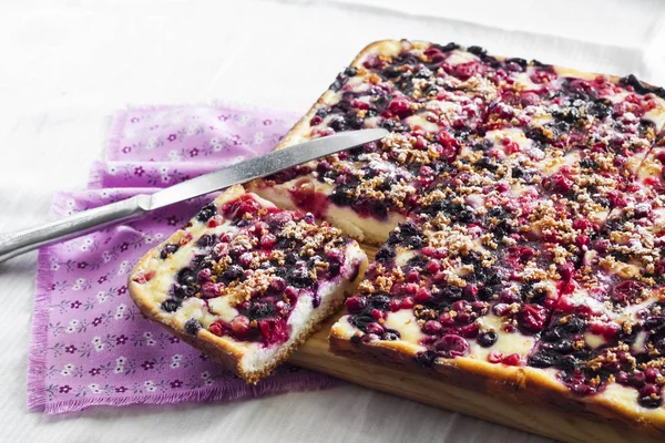 Вкусный пирог с ягодным ассортиментом и творогом нарезанный на квадратные ломтики на деревянной доске — стоковое фото