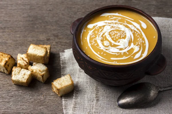 Гарбузовий суп з вершками та насінням кунжуту з грінками на дерев'яному фоні — стокове фото