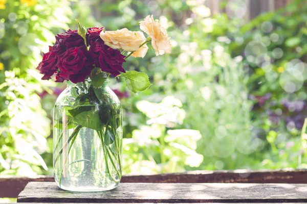 Vintage rose bouquet in glass jar on blurred green garden background in sunny summer day — Stock Photo, Image