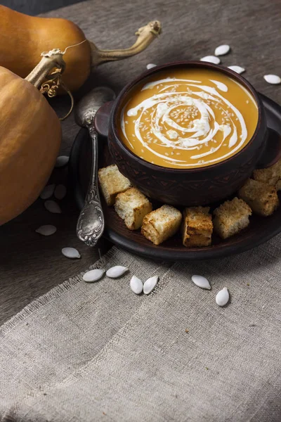Гарбузовий суп з вершками та насінням кунжуту в коричневій керамічній мисці на дерев'яному фоні. Копіювати простір — стокове фото