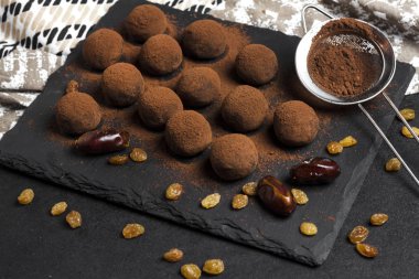 Siyah tabakta servis edilen kurutulmuş meyve, ceviz ve çiğ kakao tozlu ev yapımı vejetaryen mantarları..