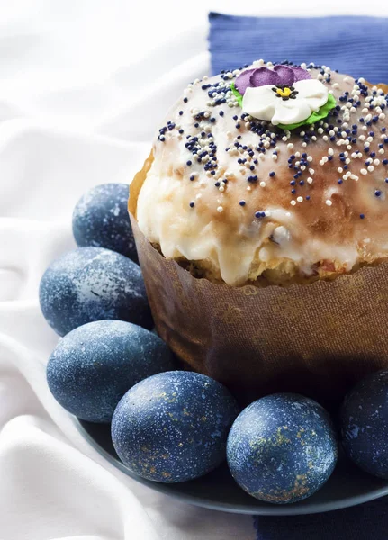 Pastel de Pascua decorado con flor de azúcar y huevos de color azul en un plato sobre fondo de tela blanca y azul —  Fotos de Stock