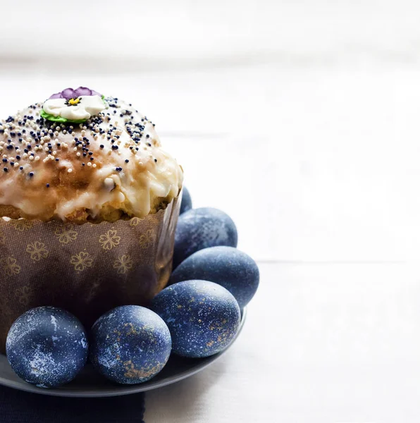 Gâteau de Pâques décoré de fleurs de sucre et d'œufs de couleur bleue sur une assiette sur fond de tissu blanc et bleu avec espace de copie. Les œufs étaient colorés en bleu avec une décoction d'hibiscus — Photo