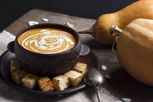 Soupe de citrouille à la crème et graines de sésame dans un bol en céramique marron sur fond en bois — Photo