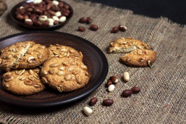 Kahverengi tabakta ev yapımı fıstık kurabiyeleri ve arka planda çiğ fıstık.