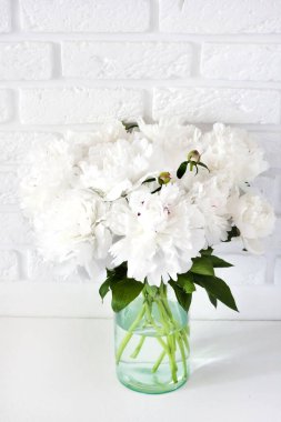 Cam bir vazoda beyaz şakayık buketi beyaz bir kırık duvar zemininde fotokopi alanı ile