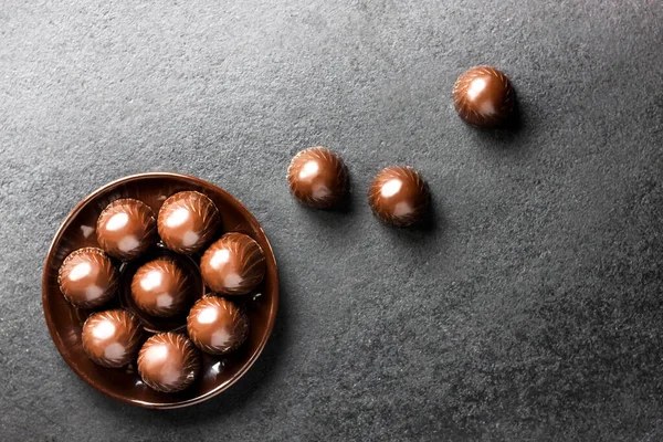 コピースペースの黒い背景にプレート上のチョコレートキャンディー フラットレイアウト トップビュー — ストック写真