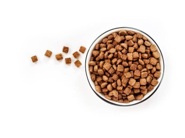 Beyaz arka planda izole edilmiş beyaz bir seramik kasede kurutulmuş hayvan yiyeceği. Düz yerde, üst tarafta. Boşluğu kopyala