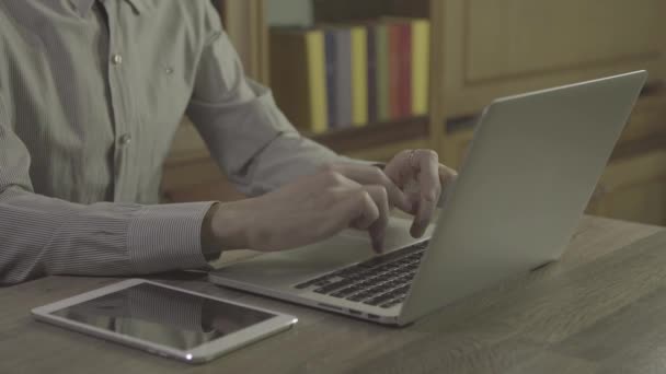 Молодой человек руки с помощью ноутбука на столе, 4k ungraded кадры сняты в 24 кадров в секунду — стоковое видео