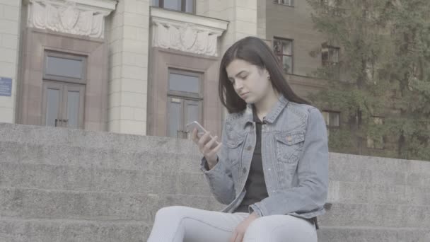 彼女のタッチ スクリーン携帯電話 4 k を使用して魅力的な若い女性 — ストック動画