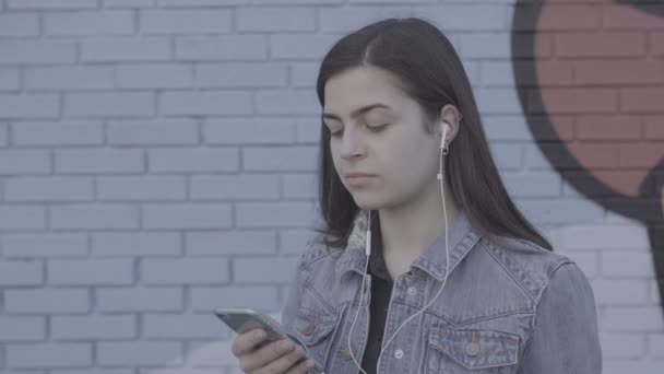 Mujer joven escuchando música en la ciudad 4K — Vídeos de Stock