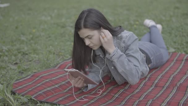 Mujer joven escuchando música en el parque 4K — Vídeos de Stock