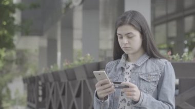Genç kadın bir smartphone cep telefonu ile 4 k kredi kartı ile ödeme