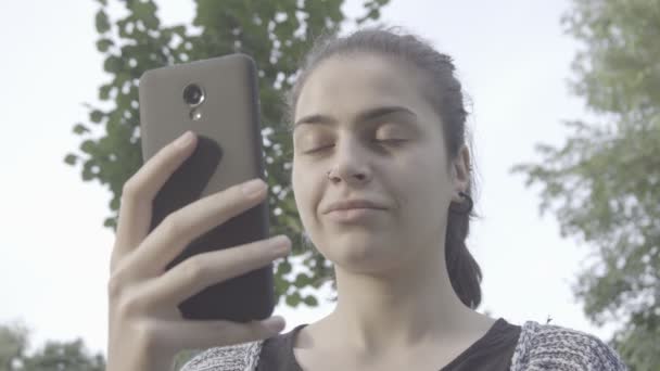 Mujer joven atractiva usando su teléfono de pantalla táctil 4K — Vídeo de stock