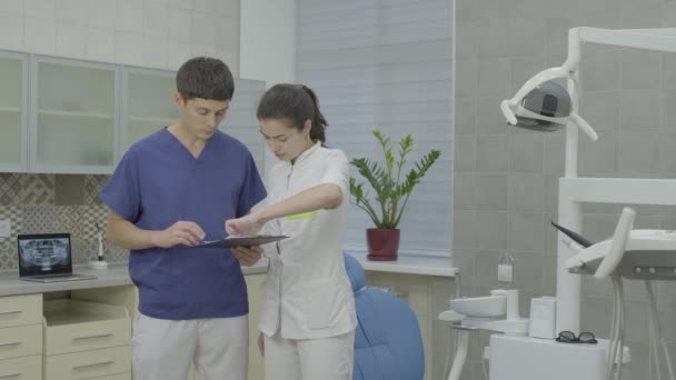 Un joven y atractivo médico comprueba la tarjeta médica del paciente . — Vídeos de Stock