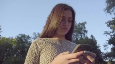 4 k parkta onun değmek perde telefon kullanarak çekici genç kadın 