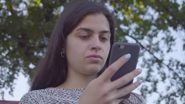 Attrayant jeune femme en utilisant son téléphone à écran tactile dans le parc 4K — Video