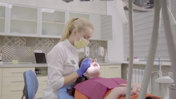 Женщина-дантист лечит молодую привлекательную женщину — стоковое видео