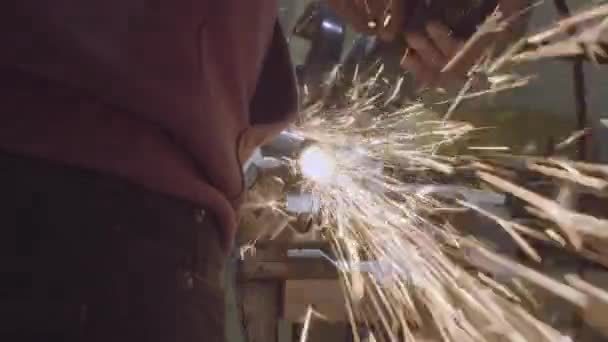 장인은 작업장에서 디스크 분쇄기로 금속을 톱질합니다 뜨거운 금속에서 나오는 불꽃의 — 비디오