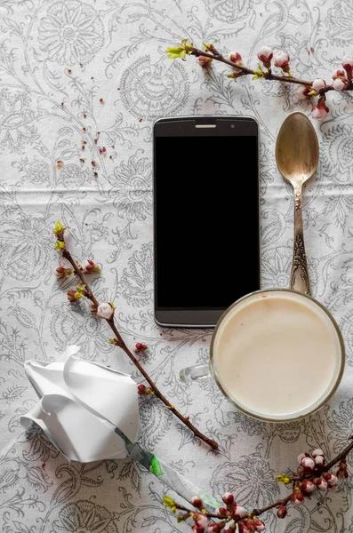 Telefono e una tazza di caffe 'caldo. Rami primaverili — Foto Stock